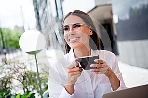 Photo of gorgeous positive girl toothy smile contemplate hold fresh hot coffee mug street cafe outside