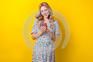 Photo of gorgeous positive lady wear stylish sarafan hold iphone read instagram facebook post isolated on yellow color