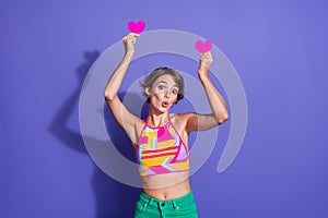 Photo of gorgeous youngster girl wear trendy nice clothes raise hands hold paper symbol heart figure isolated on purple