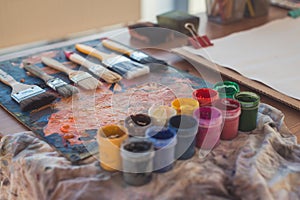 Photo of gouache and watercolor with brushes set in art studio. Oil paints smeared on palette
