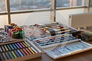 Photo of gouache and watercolor with brushes set in art studio. Oil paints smeared on palette
