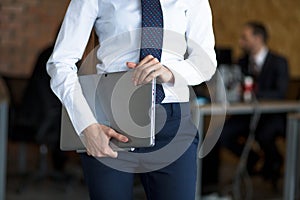 A photo of grey laptop, holded by businesswoman`s arms