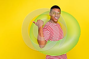 Photo of guy hipster tourist point thumb empty space ads ring wear red striped t-shirt isolated over shine yellow color