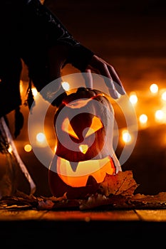 Photo of halloween pumpkin cut in shape of face with witch`s hand