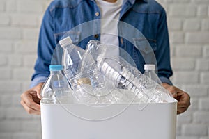 Photo of hand holding white recycling bin with many plastic bottles