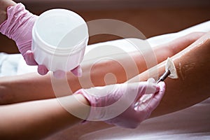 Photo of hands in pink medical gloves applying a cooling cosmetic gel with a brush. Preparing the skin for the procedure