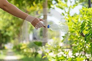 Photo of hands throwing away plastic bottles in nature