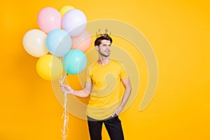 Photo of handsome boast guy holding air balloons golden crown on head shows high social status wear casual t-shirt black