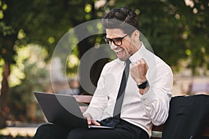 Photo of handsome businessman in suit sitting on bench in green