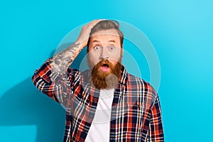 Photo of handsome funny young businessman bearded with tattoo his arm touch head oops mistake confused isolated on blue