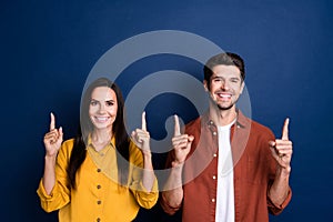 Photo of handsome guy attractive lady toothy smile indicate fingers up empty space isolated on blue color background