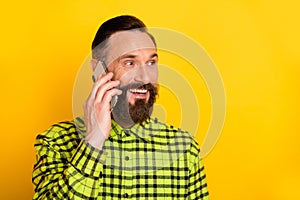 Photo of handsome man happy positive smile call talk speak conversation smartphone isolated over yellow color background