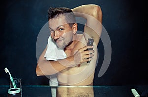 Photo of handsome man shaving his armpit
