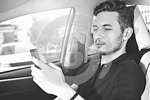 Photo of a handsome man using mobile phone while driving.