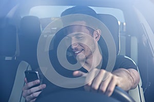 Photo of a handsome man using mobile phone while driving.