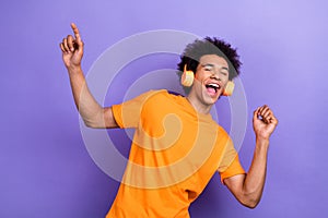 Photo of handsome overjoyed chilling guy dancing listen earphones ac dc rock roll music itunes advert isolated on purple photo