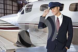 Portrait of handsome young pilot standing in front of private airplane