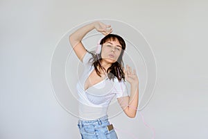 Photo of a happy brunette with pink headphones in white blouse and denim skirt