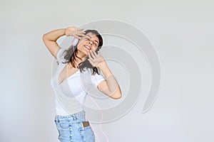 Photo of a happy brunette with pink headphones in white blouse and denim skirt