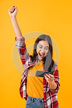 Photo of happy brunette woman using cellphone ad making winner gesture