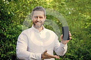 photo of happy businessman showing app with copy space outdoor