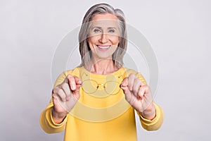 Photo of happy cheerful beautiful smiling mature woman give you glasses bad eyesight isolated on grey color background