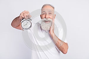 Photo of happy cheerful old man hold hand cheekbone clock alarm good mood  on grey color background photo