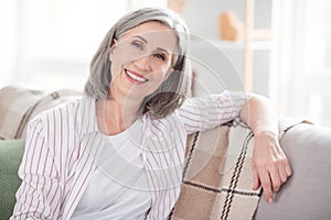 Photo of happy cheerful old pretty lady sit couch smile good mood smile indoors inside house home apartment