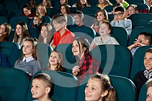 Photo of happy children watching movie in the cinema and laughing.