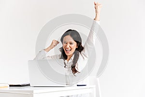 Photo of happy chinese businesswoman with long dark hair screaming with raised arms while working with documents and