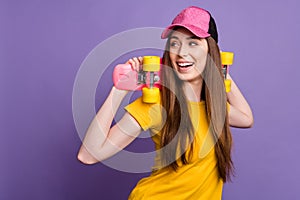Photo of happy dreamy young happy woman look empty space hold longboard isolated on purple color background