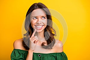 Photo of happy dreamy young woman hold finger chin smile look empty space  on yellow color background