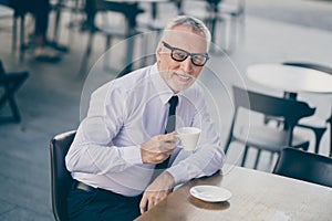 Photo of happy elderly businessman sit drink coffee cafe wear formalwear glasses in city center outside