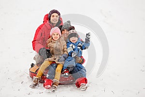 Photo of happy family with daughter and son sitting on tubing in winter