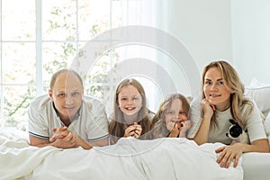 Photo of happy family lying on bed smiling in cozy home or apartment