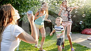 Photo of happy family playing with soap bubbles at house backyard garden. Family playing and having fun outdoors at