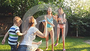 Photo of happy laughing children blowing and cathcing soap bubbles at house backyard. Family playing and having fun