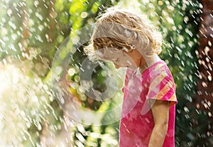 Photo of happy little girl standing under summer rain