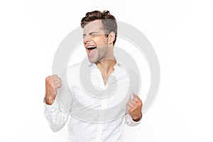 Photo of happy man 30s rejoicing and clenching fists, isolated o