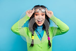 Photo of happy nice amazed young woman hold fingers glasses surprised reaction isolated on shine blue color background