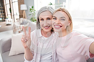 Photo of happy positive nice woman and old lady parent make selfie v-sign smile indoors inside house home