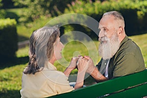 Photo of happy positive old retired people woman man sit bench hold hands nature green outdoors in urban park
