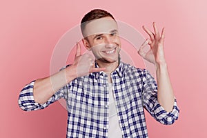 Photo of happy positive smile man make call me gesture phone show okay sign isolated on pink color background