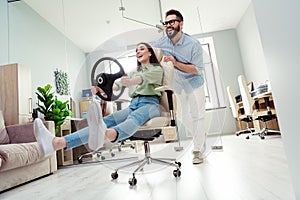 Photo of happy smiling coworkers wear shirts playing riding automobile indoors workplace workstation