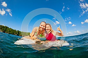 Photo of happy surfer girls sitting on surf boards
