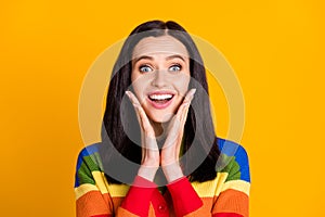 Photo of happy surprised young woman excited amazed news information hands touch cheeks isolated over yellow color