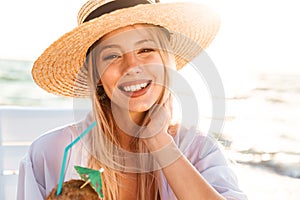 Photo of happy young woman 20s in summer straw hat laughing, and