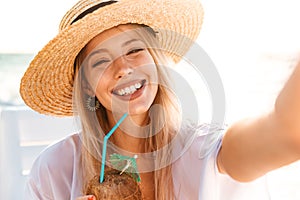 Photo of happy young woman 20s in summer straw hat laughing, and
