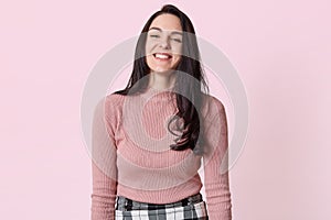 Photo of happy young woman with beautiful dark long hair laughing isolated over pink background, having fun with her friends,