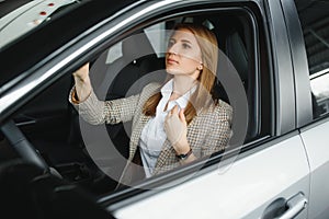 Photo of happy young woman sitting inside her new car. Concept for car rental.